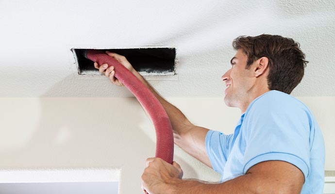 Person cleaning duct with equipment