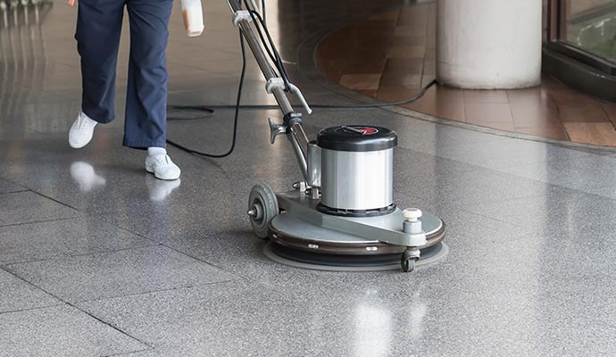 Person cleaning tile floor with equipment