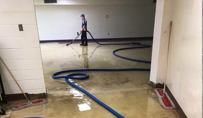 Professional extracting water from a flooded floor