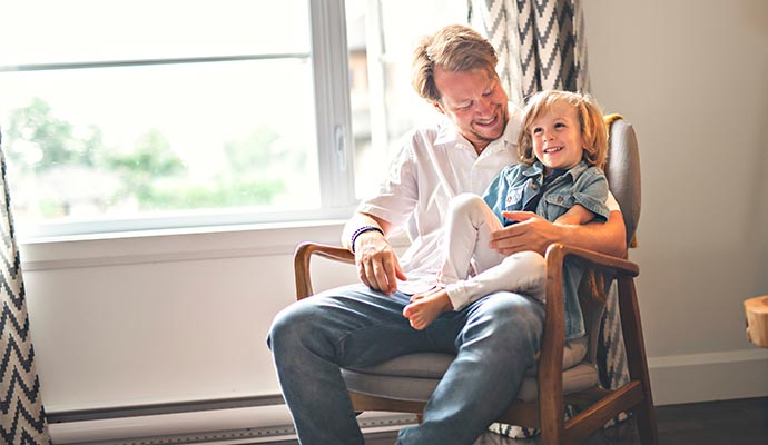 Father smiling and spending quality time with his daughter sitting on an armchair