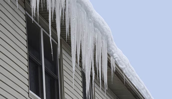 Icicles and heavy snow hanging from a roof gutter