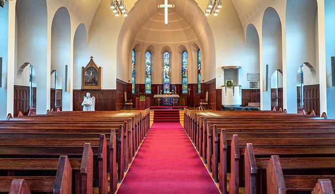 Interior view of a clean church Church interior with wooden pews, red carpet aisle, and stained glass windows