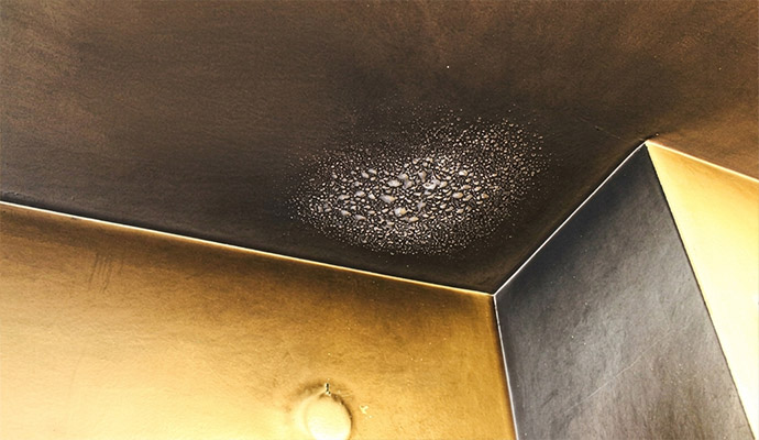 Heavy smoke residue and soot damage on a ceiling corner and wall surface