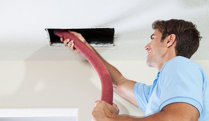 A person cleaning duct vent A person cleaning duct vent
