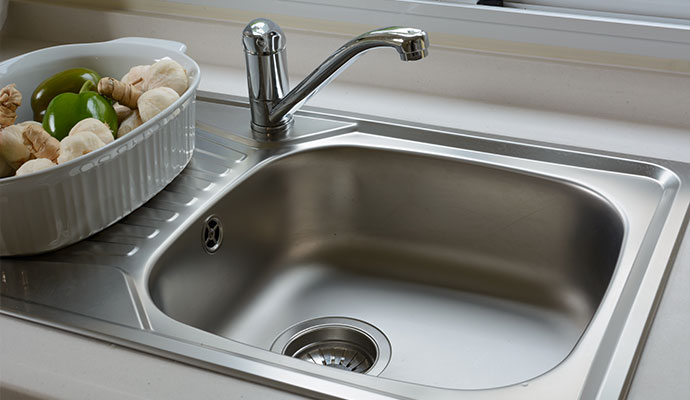 Clean stainless steel kitchen sink with faucet after overflow cleanup