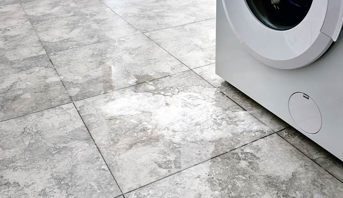 Water flooding a laundry room floor from an overflowing washing machine