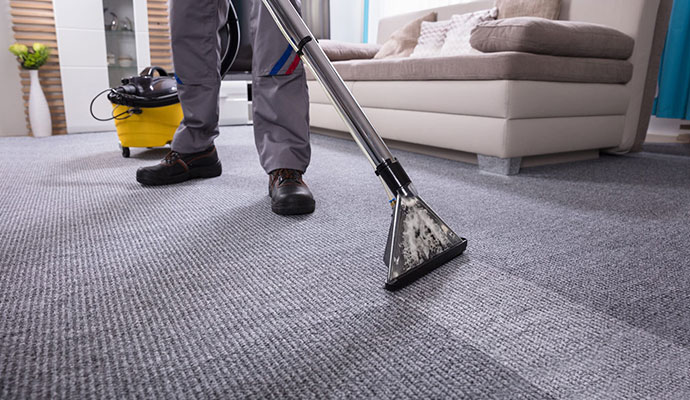 Worker cleaning carpet with equipment